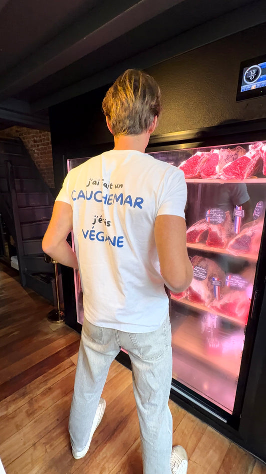 Homme de dos portant le t-shirt J'ai fait un cauchemar, j'étais végane devant une vitrine de viande maturée