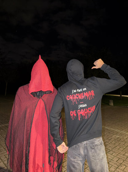Pull noir Halloween J'ai fait un cauchemar édition sang porté de dos, à côté d'une cape rouge