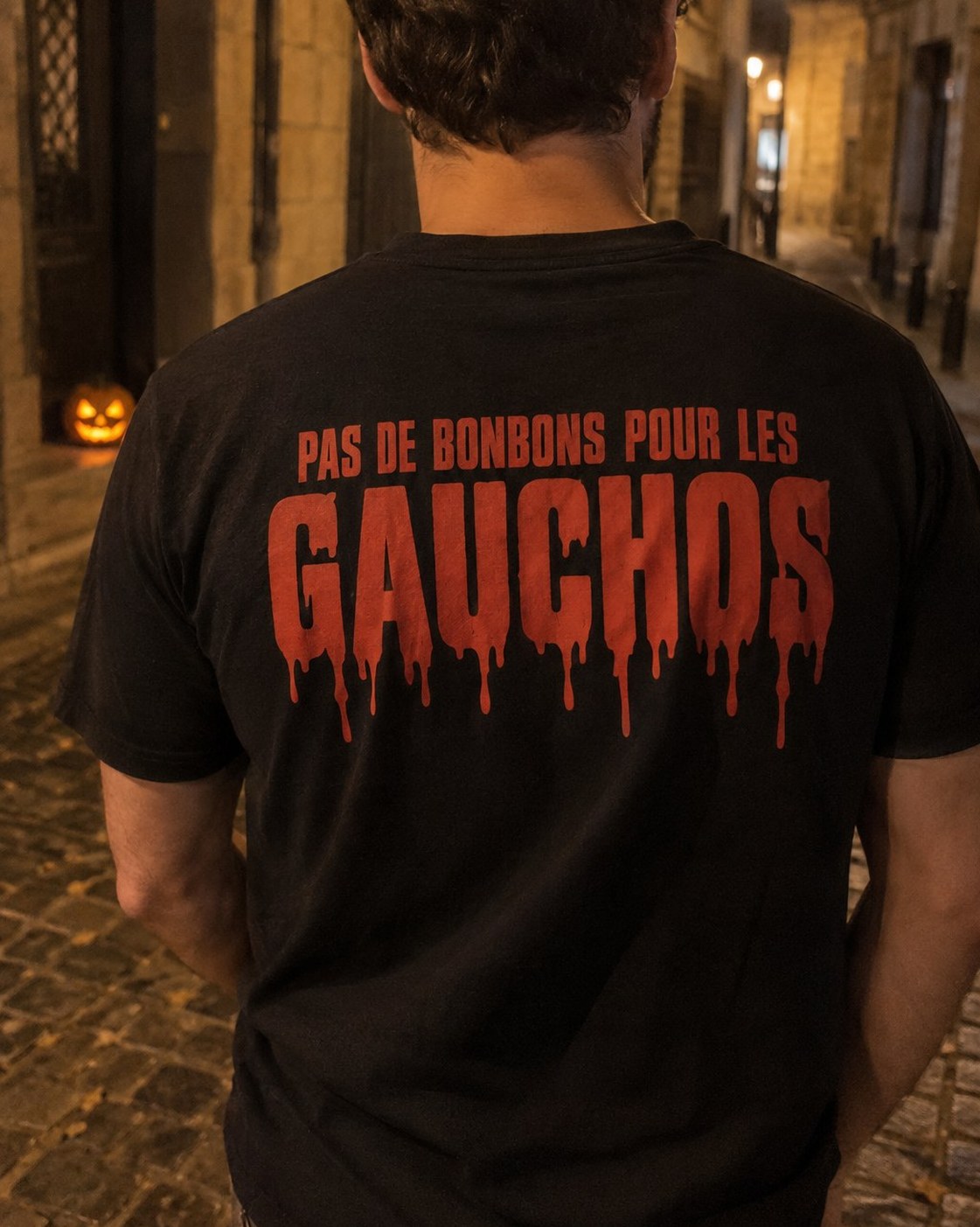 Gros plan du t-shirt noir Pas de bonbons pour les gauchos porté de nuit, citrouille d'Halloween au sol, coloris noir