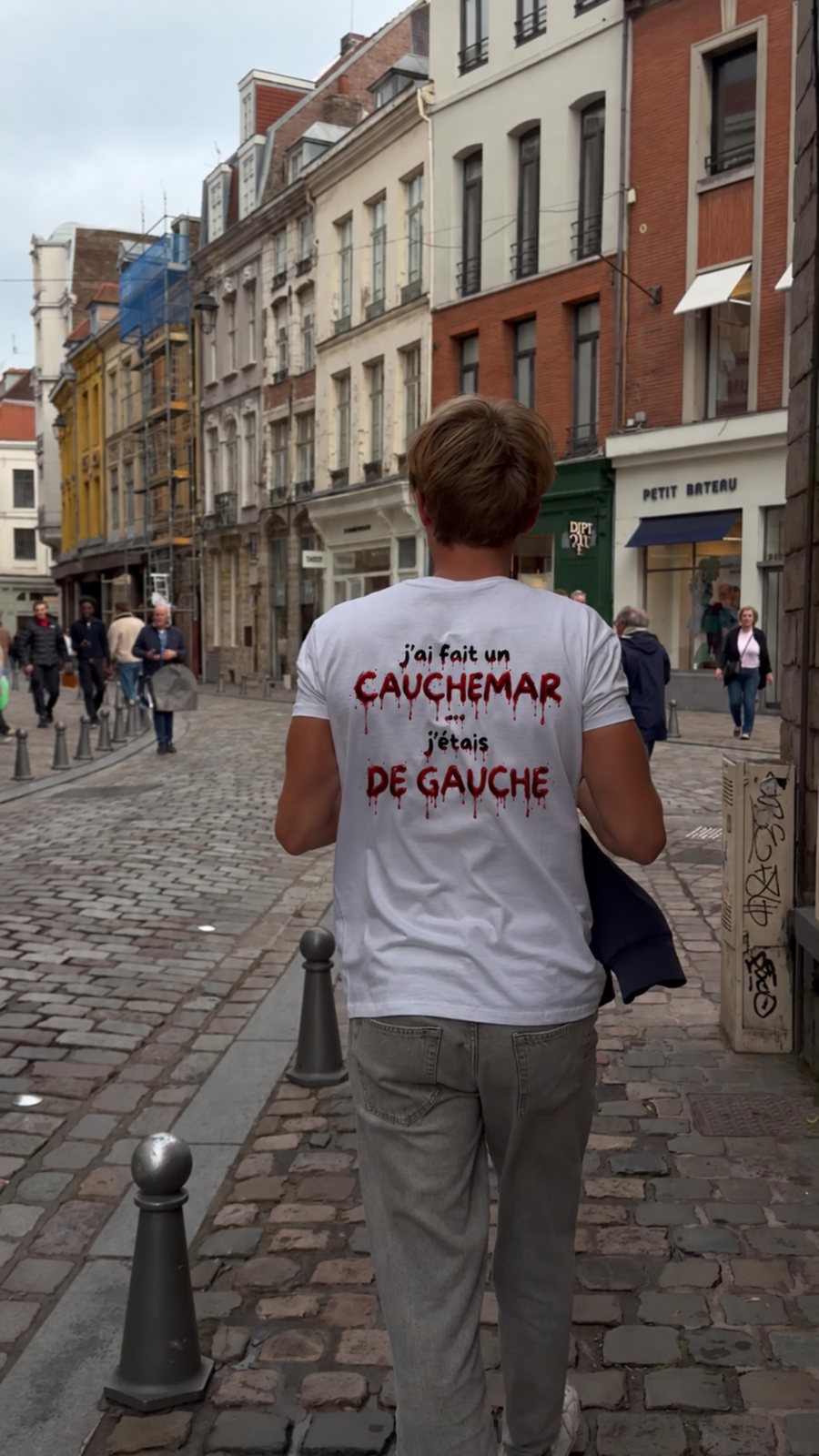 T-shirt J'ai fait un cauchemar, j'étais de gauche, édition sang, porté de dos dans une rue en briques, coloris blanc