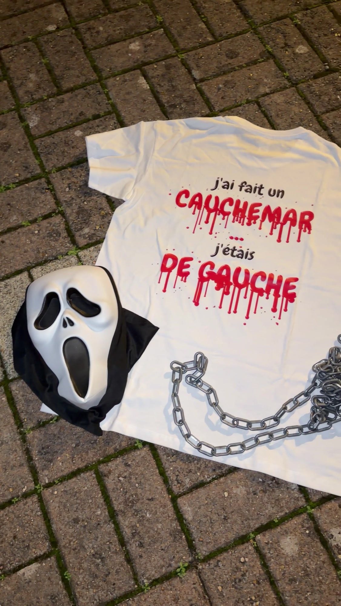 T-shirt Halloween J'ai fait un cauchemar, édition sang, posé sur les pavés avec un masque Scream et des chaînes, coloris blanc