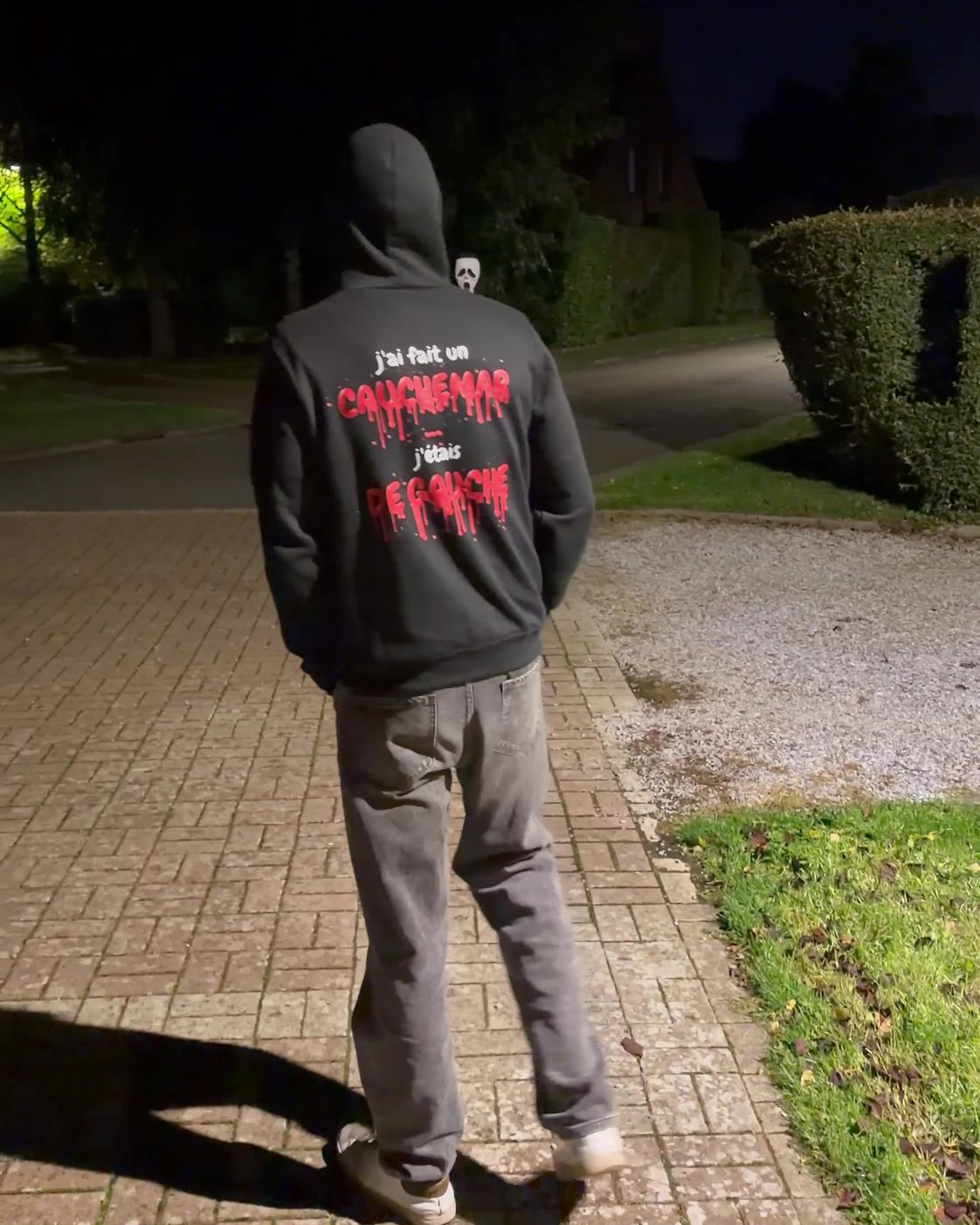 Homme de dos de nuit portant le pull à capuche Halloween J'ai fait un cauchemar Hustle Wear, encre rouge sang, un Scream approche derrière lui