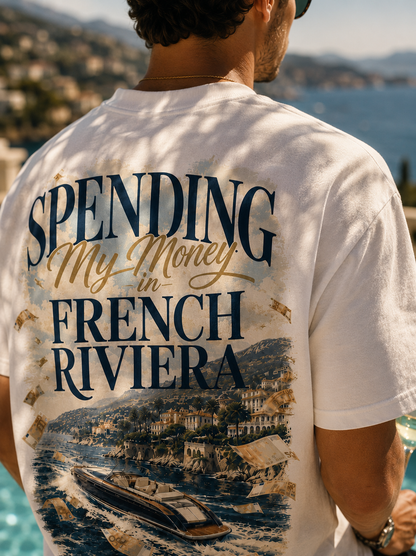 Homme portant le t-shirt Spending My Money in French Riviera Hustle Wear en terrasse vue mer, de dos